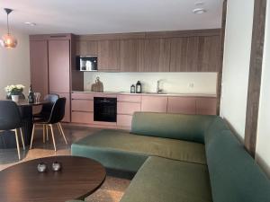 a living room with a green couch and a kitchen at B2 Lakeside Suite Polku Hotel in Vihti