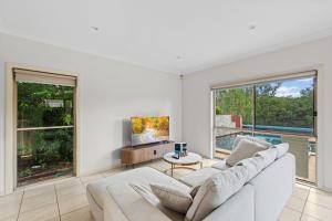 a living room with a white couch and windows at Front Lake View 4Bed Home with Pool and Mins to Mall in Doolandella
