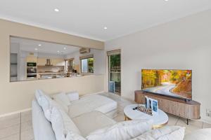 a living room with a white couch and a tv at Front Lake View 4Bed Home with Pool and Mins to Mall in Doolandella