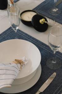 a white plate on a table with wine glasses at Front Lake View 4Bed Home with Pool and Mins to Mall in Doolandella