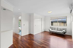 an empty living room with a couch and a window at Front Lake View 4Bed Home with Pool and Mins to Mall in Doolandella