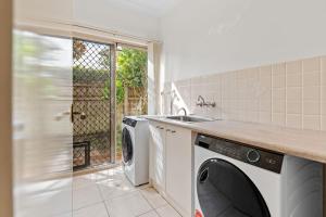 a kitchen with a washing machine and a sink at Front Lake View 4Bed Home with Pool and Mins to Mall in Doolandella