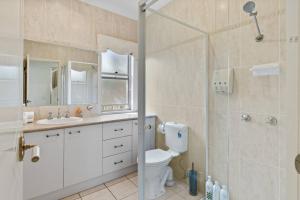 a bathroom with a shower and a toilet and a sink at Front Lake View 4Bed Home with Pool and Mins to Mall in Doolandella