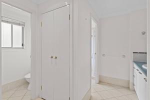 a white bathroom with a toilet and a sink at Front Lake View 4Bed Home with Pool and Mins to Mall in Doolandella