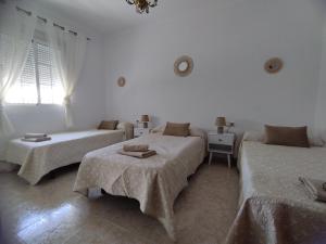 a white room with two beds and a couch at Casa Paco & Carmela in Algodonales +34 photos