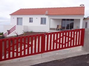 una cerca roja frente a una casa en Casa da Vigia en Calheta de Nesquim