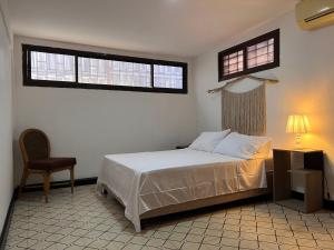 a bedroom with a bed and a chair and two windows at Habitación privada apartamento in Santa Marta