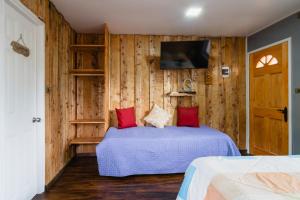 プコンにあるPucón Rec-Lodge Cabaña Fiuのベッドと壁掛けテレビのある寝室