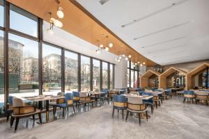a restaurant with tables and chairs and large windows at Hilton Garden Inn Xuzhou Pengcheng Square in Xuzhou
