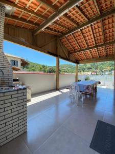 a patio with a table and chairs and a wooden roof at Casa Aluguel Porto Belo in Porto Belo