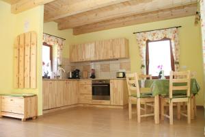 a kitchen with wooden cabinets and a table and chairs at BONI APARTMAN Hegykő in Hegykő