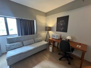 a room with a couch and a desk with a computer at Hotel Live Lodge Ibirapuera UH519 in Sao Paulo