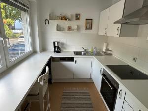 a kitchen with white cabinets and a sink and a window at GartenOase in der Universitätsstadt 3 Zimmer Haus mit Parkplatz in Erlangen