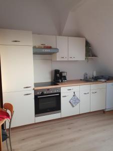 a kitchen with white cabinets and a black oven at Monteurwohnung Sendberg Blick in Frielendorf