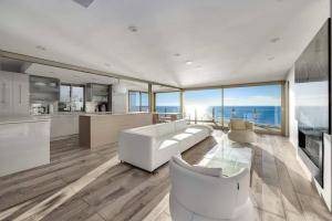 a living room with a white couch and a kitchen at Hi-Tech Hideaway - Modern & Ocean Front! in Solana Beach