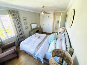 a bedroom with a bed and a chair at Granny Reed's Cottage in Port Alfred