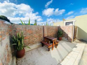 a brick wall with a wooden bench and plants at Granny Reed's Cottage in Port Alfred +3 photos