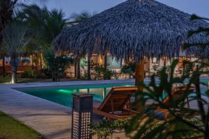 a resort with a swimming pool and a straw hut at Vila Selvagem Hotel Contemporaneo in Fortim