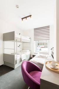a white bedroom with a purple chair and a bed at Pokoje Cinema in Poznań