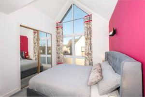 a bedroom with a bed and a pink wall at Beachwood Retreat in Sheringham