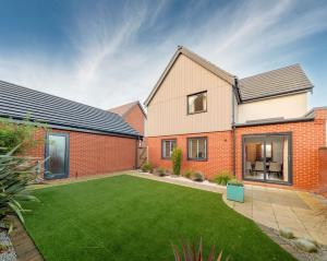 a brick house with a lawn in the yard at Beachwood Retreat in Sheringham