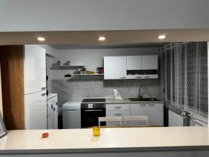 a kitchen with white cabinets and a white refrigerator at Apartman Ana in Bjelovar