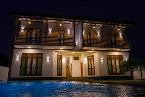 a house at night with a swimming pool in front at Villa Elegant Oasis in Horana