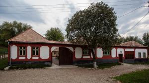 uma casa vermelha e branca com uma árvore em frente em Valea Verde Retreat Transilvania em Cund