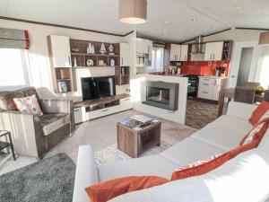 a living room with a white couch and a fireplace at Downtime Lodge in Morpeth