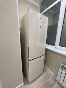 a white refrigerator in a kitchen next to a window at Apartments comfort new, Aktau 16 77 in Aktau