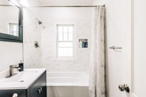 a white bathroom with a shower and a sink at Minnehaha Falls Hideaway in Minneapolis