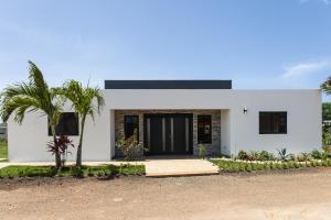 een wit huis met een palmboom ervoor bij Casa De lo Mio in Sosúa