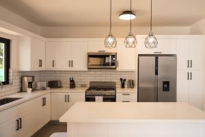 een keuken met witte kasten en een roestvrijstalen koelkast bij Casa De lo Mio in Sosúa