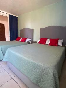 two beds in a hotel room with red pillows at 4 VENATOR House Boutique in León