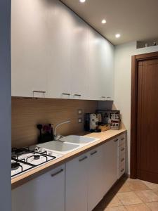 una cucina con mobili bianchi, un lavello e una stufa di Residenza Fonticella a Rivisondoli