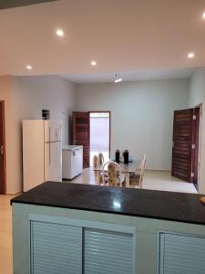 a kitchen with a table and a white refrigerator at Casa da Bênção - Praia de Moitas in Amontada