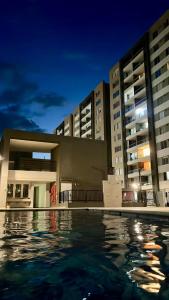 une piscine d'eau devant les bâtiments la nuit dans l'établissement Nuevo apartamento de lujo con balcón wifi AC piscina, à Barranquilla