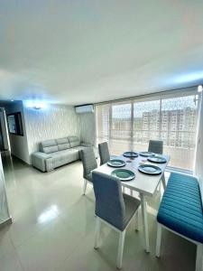 un salon avec une table et des chaises blanches dans l'établissement Nuevo apartamento de lujo con balcón wifi AC piscina, à Barranquilla