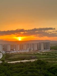 une ville au soleil couchant en arrière-plan dans l'établissement Nuevo apartamento de lujo con balcón wifi AC piscina, à Barranquilla