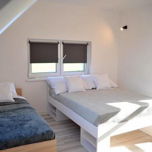 a white bedroom with a bed and two windows at Dom Nad Potokiem Średnia Wieś in Hoczew