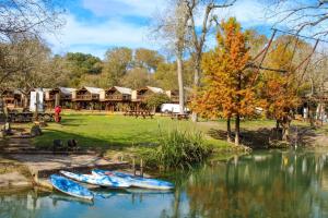 two boats sitting in the water in front of a lodge at Waterfront Prairie Flower Treehouse in Seguin