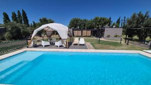 a large swimming pool with a gazebo and chairs at casArtero eco posada in San Rafael