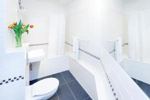 a white bathroom with a toilet and a vase of flowers at The Maybach - rooftop living XBerg, 1BR, 1 living room, group & family friendly, 2 - 4 Guests in Berlin +11 photos