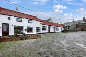 a group of white buildings in a yard at Minnows Rest - North East Escapes in Seahouses