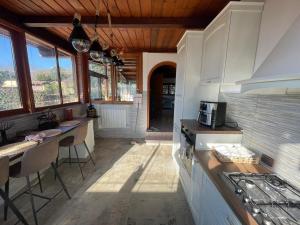 Una cocina con estufa y algunas sillas y ventanas. en villa praxedes, en Nettuno