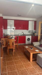 a kitchen and living room with red cabinets and a table at Baltar in Sanxenxo