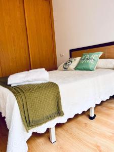 a bedroom with a white bed with a green pillow at Baltar in Sanxenxo