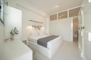 a white bedroom with a bed and a desk at Flisvos Beach Apartments in Naxos Chora