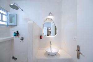 a white bathroom with a sink and a mirror at Flisvos Beach Apartments in Naxos Chora