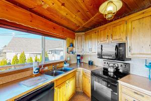 a kitchen with wooden cabinets and a large window at Carousel House in Pacific City in Pacific City